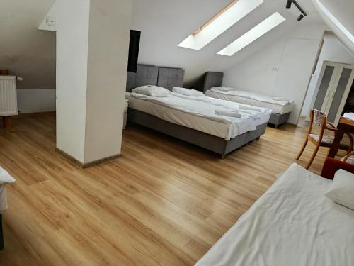 a bedroom with three beds and a wooden floor at Checz Gościnna- pokoje,sauna,jacuzzi, sala konferencyjna in Grzybno