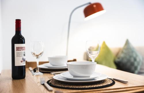 a bottle of wine sitting on a table with glasses at Hereford Central Apartment in Hereford