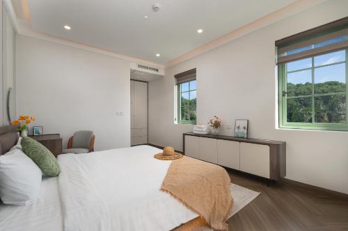 a white bedroom with a large bed and a window at La isla Apartments & Villas - Sea View & Fireworks Phu Quoc in Phu Quoc