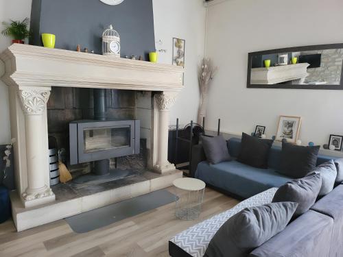 a living room with a fireplace and a blue couch at Gite des Coteaux Pmr in Sainte-Maure-de-Touraine