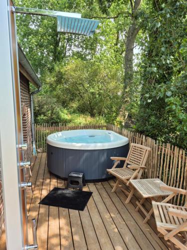a hot tub on a wooden deck with two chairs at Au pied du frêne in Herzeele