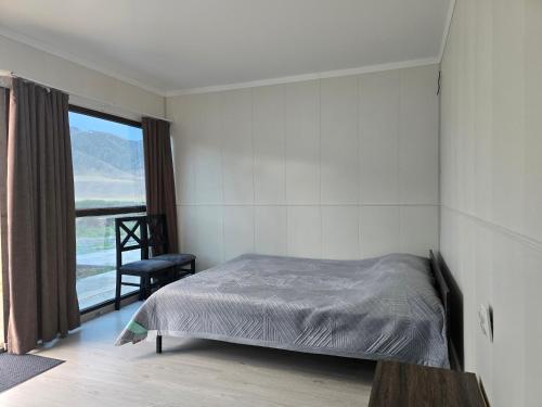 a bedroom with a bed and a chair and a window at GlamPark in Kurmenty