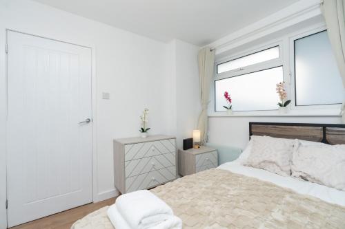 a white bedroom with a bed and two windows at Open Mind Property -8 Guests, 4Beds & Free Parking in Hayling Island