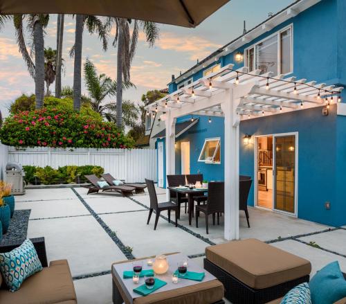 a patio with a blue house with a pergola at Sea La Vie by Paradise Retreats in Ventura