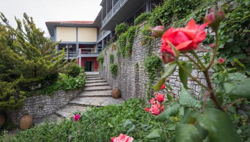 uma parede de tijolos com um caminho e flores vermelhas em Theoxenia Hotel em Andrítsaina