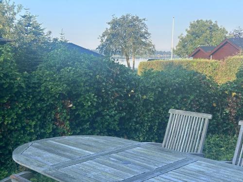 a wooden table and chairs in a yard with bushes at House with whirlpool, lake view and access in Sunds