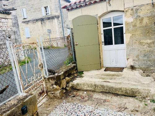 a green door on the side of a building at Petit Chai au coeur de village in Saint-Christophe-des-Bardes
