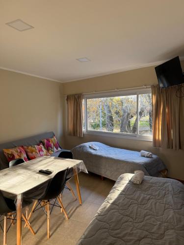 a room with two beds and a table and a window at Las Margaritas in Pila