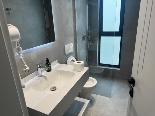 a bathroom with a sink and a toilet and a mirror at Hotel Sisana in Vlorë