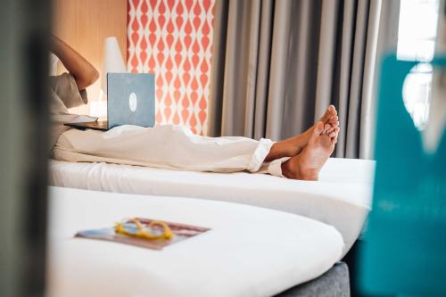 a person laying on a bed with their feet on a laptop at Stay Hotel Faro Centro in Faro