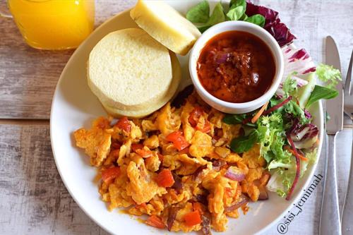 a plate of food with a salad and a sandwich and salsa at Mainstay Luxury Hotel in Ibadan
