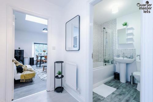 a white bathroom with a tub and a sink at 2 Bedroom Top Floor Apartment that Sleeps 4 in Birkenhead