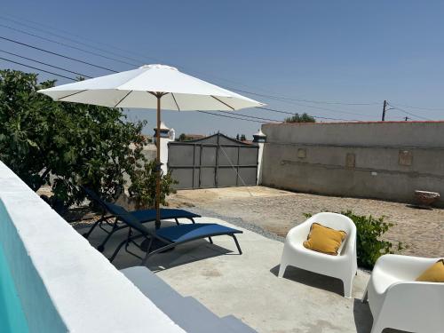 a patio with two chairs and an umbrella at Casa dos Avós in Campinho