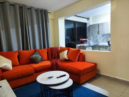 a living room with an orange couch and a table at Platinum Place in Kikuyu