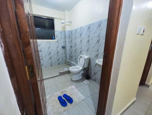 a bathroom with a toilet and a pair of blue slippers at Platinum Place in Kikuyu
