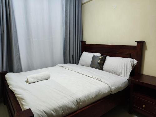 a bed with white sheets and a pillow on it at Platinum Place in Kikuyu