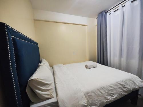 a bedroom with a bed with a blue headboard and a window at Platinum Place in Kikuyu