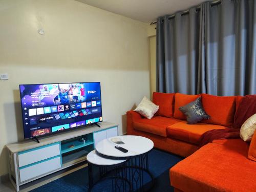 a living room with a orange couch and a flat screen tv at Platinum Place in Kikuyu
