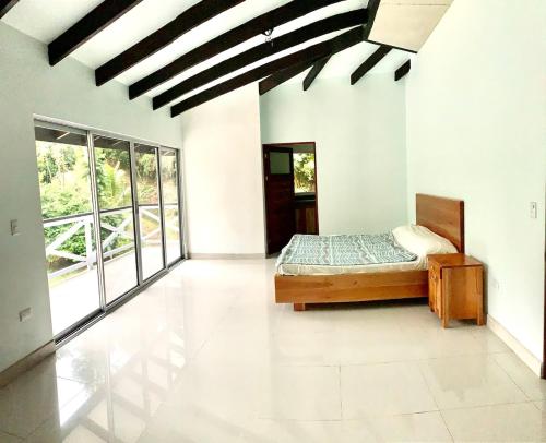 a bedroom with a bed in a room with windows at Dominical Beach 15 min Private Retreat Casa Grande in Platanillo