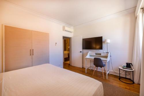a white bedroom with a bed and a desk at Pousada de Sagres in Sagres