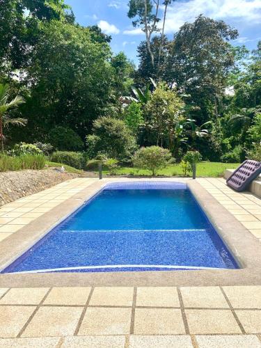 a swimming pool with blue water in a garden at Dominical Beach 15 min Private Retreat Casa Grande in Platanillo