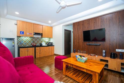a living room with a red couch and a table at Skylight BnB F203 - 2BHK with pool near Candolim beach in Candolim