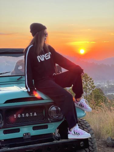 a woman sitting on the hood of a truck at Batur Cozy Bali in Kintamani