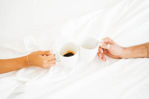two hands holding cups of coffee on a bed at Stay Hotel Faro Centro in Faro