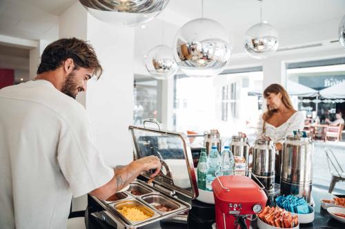 a man preparing food in a kitchen with a woman at Stay Hotel Faro Centro in Faro