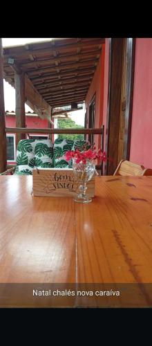 a vase of flowers sitting on top of a wooden table at Natal Chalés Nova Caraiva in Caraíva