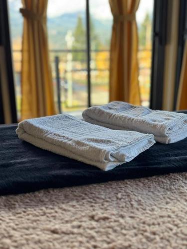 two towels sitting on top of a bed with a window at Hostel 360 Patagonia in El Bolsón