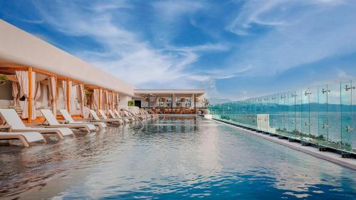 a hotel swimming pool with lounge chairs and the ocean at Unico Hotel Riviera Nayarit - Adults Only - All Inclusive in Nuevo Vallarta 
