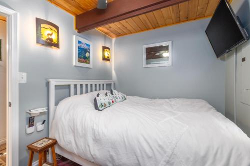 a bedroom with a white bed and a flat screen tv at Coal Creek Chalet | Creek, AC, Pet Friendly in Packwood