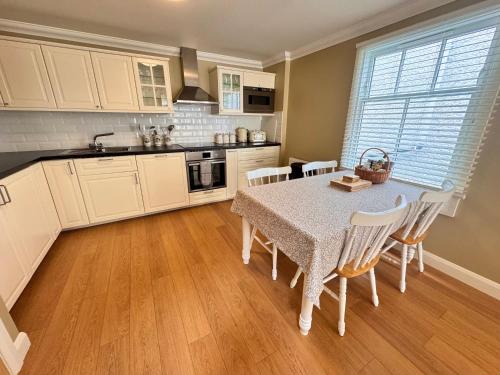 a kitchen with a table and chairs and a kitchen with white cabinets at Allt Nan Ros Cottage in Fort William