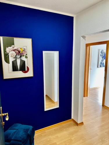 a blue wall with a vase of flowers and a mirror at Ferienwohnung nur 1 min vom See in Bregenz