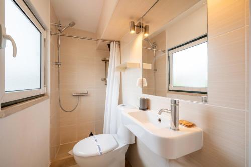 un bagno con lavandino, WC e finestra di Alfama Terrace a Lisbona