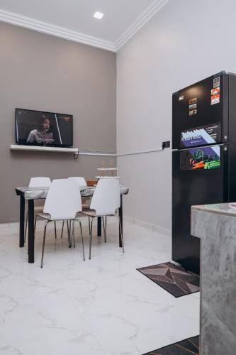 a dining room with a table and a refrigerator at Anjung Homestay & Event in Bukit Payong