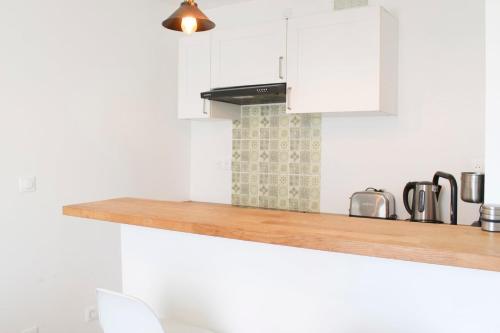 une cuisine avec des armoires blanches et un comptoir en bois dans l'établissement Attractive fully-equipped apartment near Paris, à Aubervilliers
