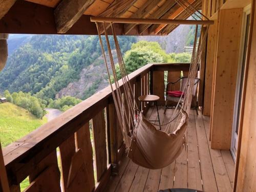 a porch with a hammock on a balcony with a view at chalet de l'eau rousse in La Lechere