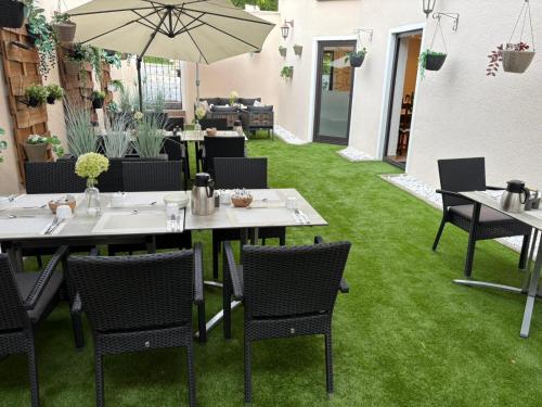 a restaurant with green grass and tables and an umbrella at Hotel Zur Linde in Saarlouis