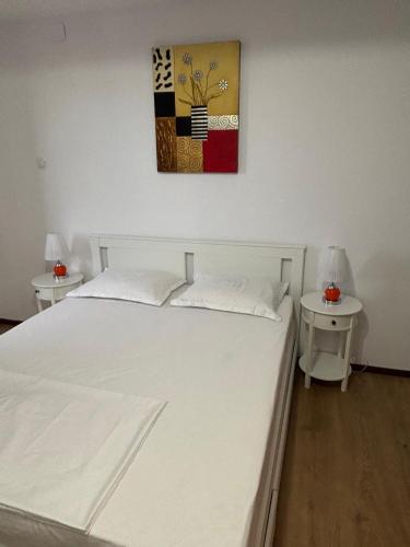 a bedroom with a white bed with two night tables at Ego Apartments in Drobeta-Turnu Severin