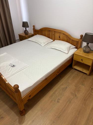 a bed with a wooden frame and two night stands at Ego Apartments in Drobeta-Turnu Severin