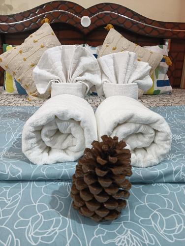 a pile of towels and a pine cone on a bed at Malta Tree Homes in Kurchhola