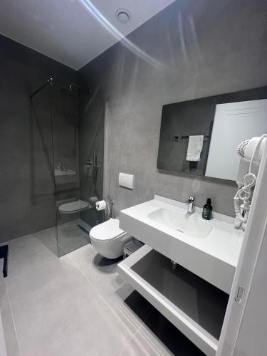 a bathroom with a white sink and a toilet at Hotel Sisana in Vlorë