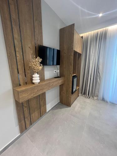 a living room with a flat screen tv on a wooden shelf at Hotel Sisana in Vlorë