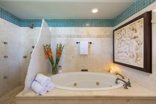 a bathroom with a tub with towels and a vase of flowers at Hale Holawa Mana-Oceanfront Sunset Beach in Haleiwa