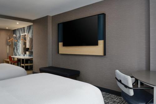 a hotel room with a bed and a tv on the wall at Tempo By Hilton Raleigh Downtown in Raleigh