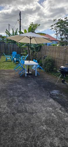 a white table and chairs with an umbrella at Escale Terre Rouge in Saint-André