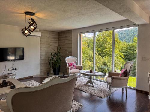 a living room with a couch and chairs and a large window at Rest House in Olovo