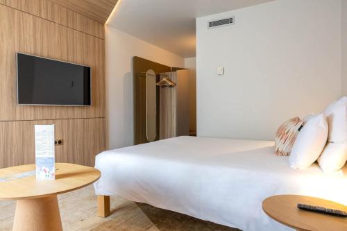 a hotel room with a bed and a flat screen tv at Novotel Toulouse Purpan Aéroport in Toulouse